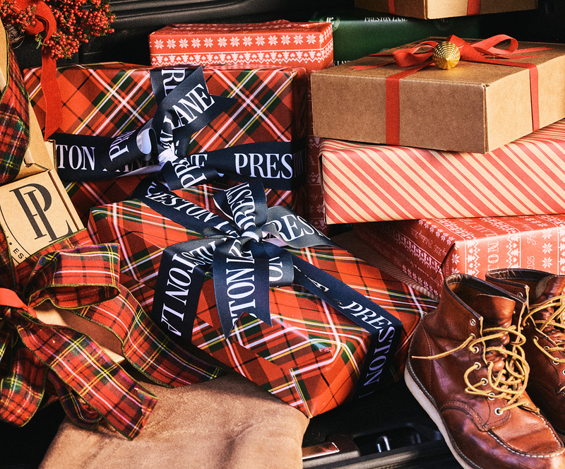 Gifts wrapped in plaid paper with decorative ribbons and a pair of brown shoes.